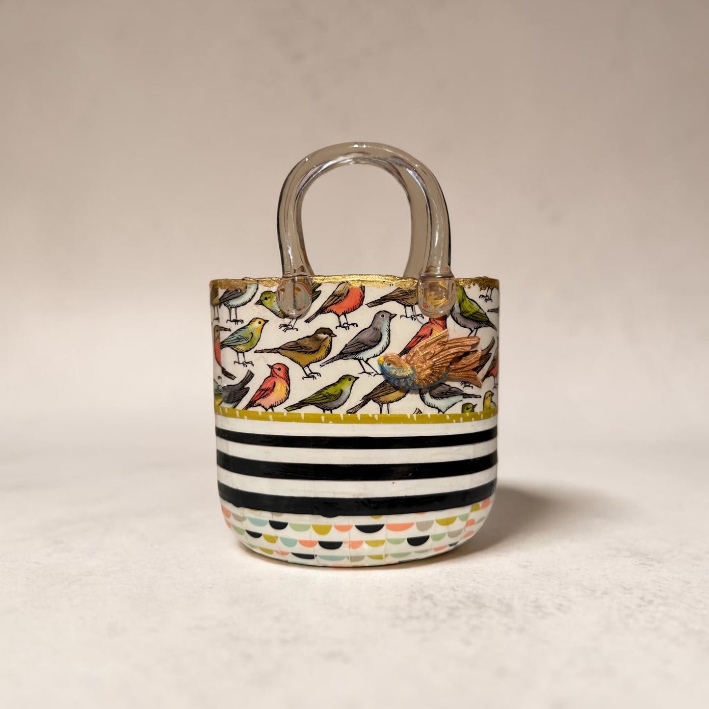 Glass purse vase with bird pattern and black and white stripes on a white background with clay bird decoration