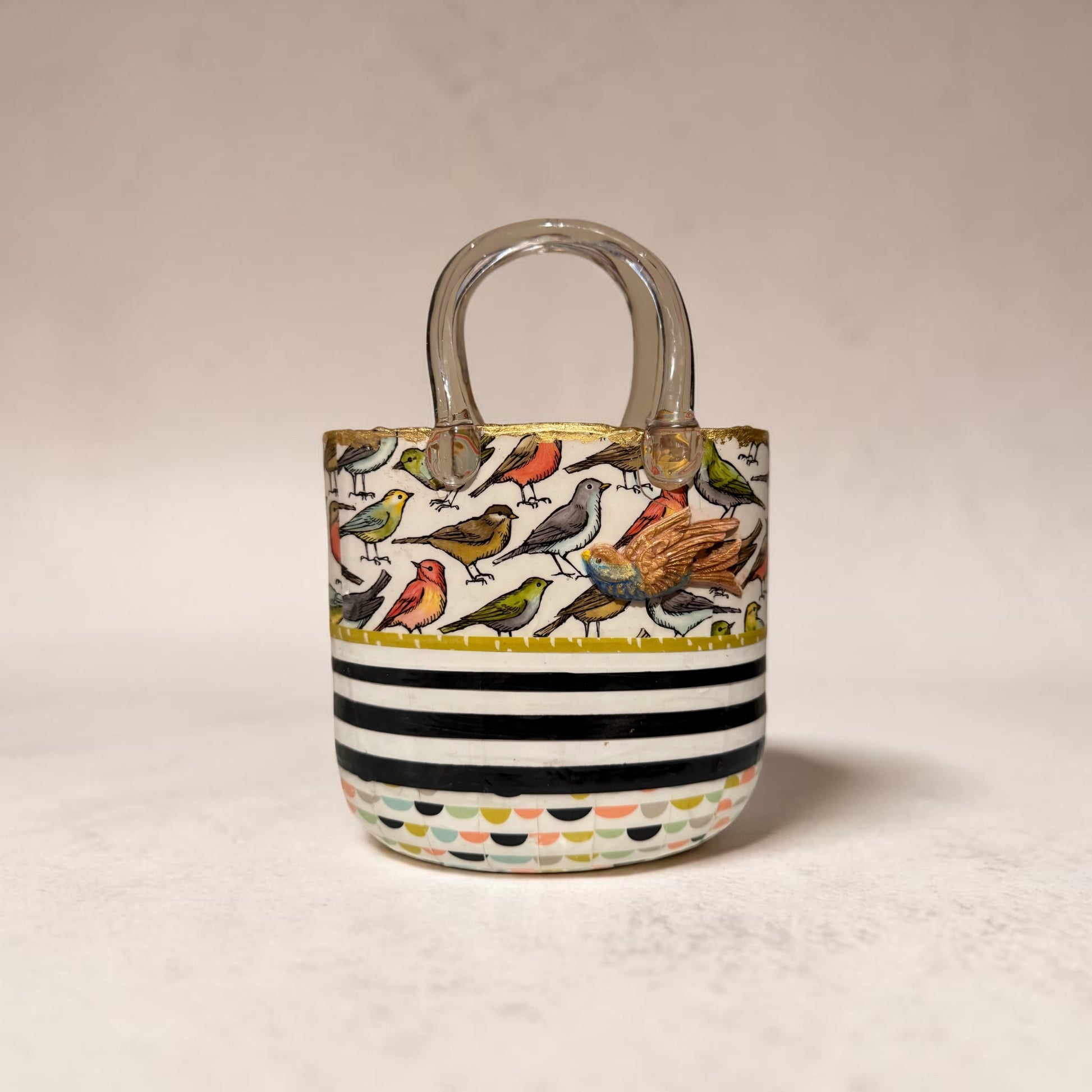 Glass purse vase with bird pattern and black and white stripes on a white background with clay bird decoration