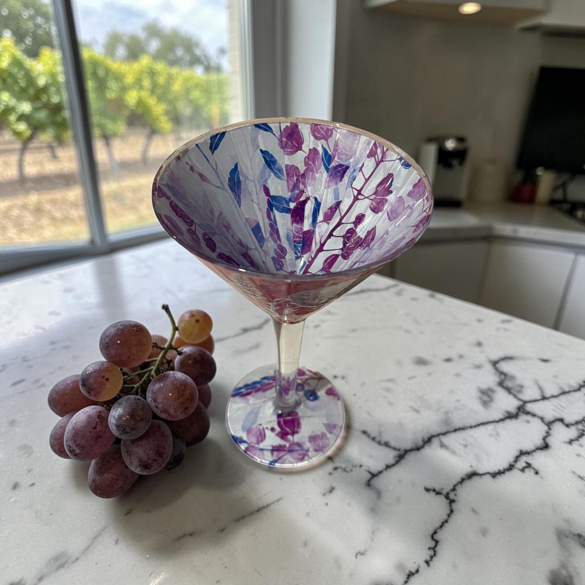 Inside of a large cocktail glass on a kitchen counter with grapes.