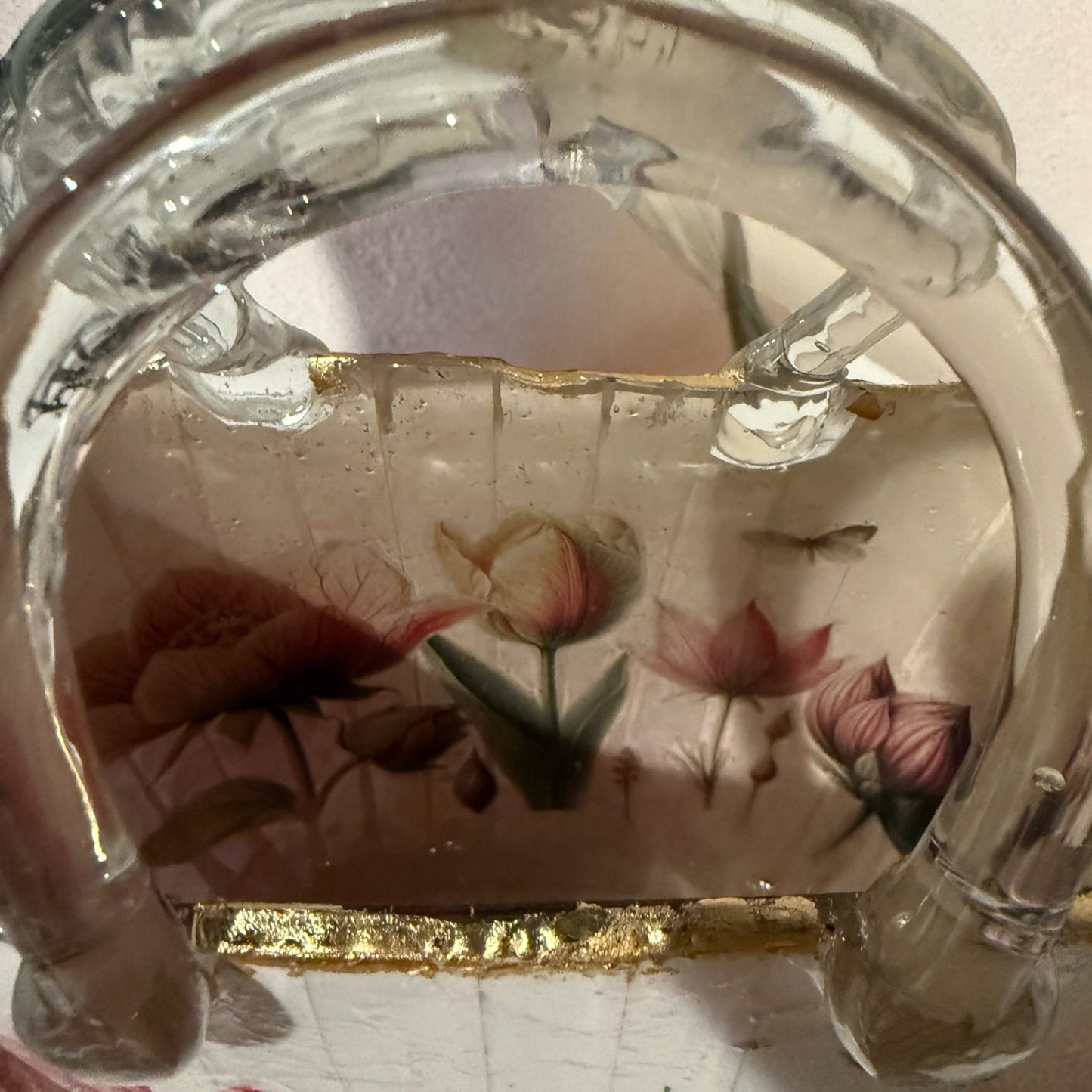 Inside of a glass purse vase with gold leaf trim.  The inside is decorated with a floral design.
