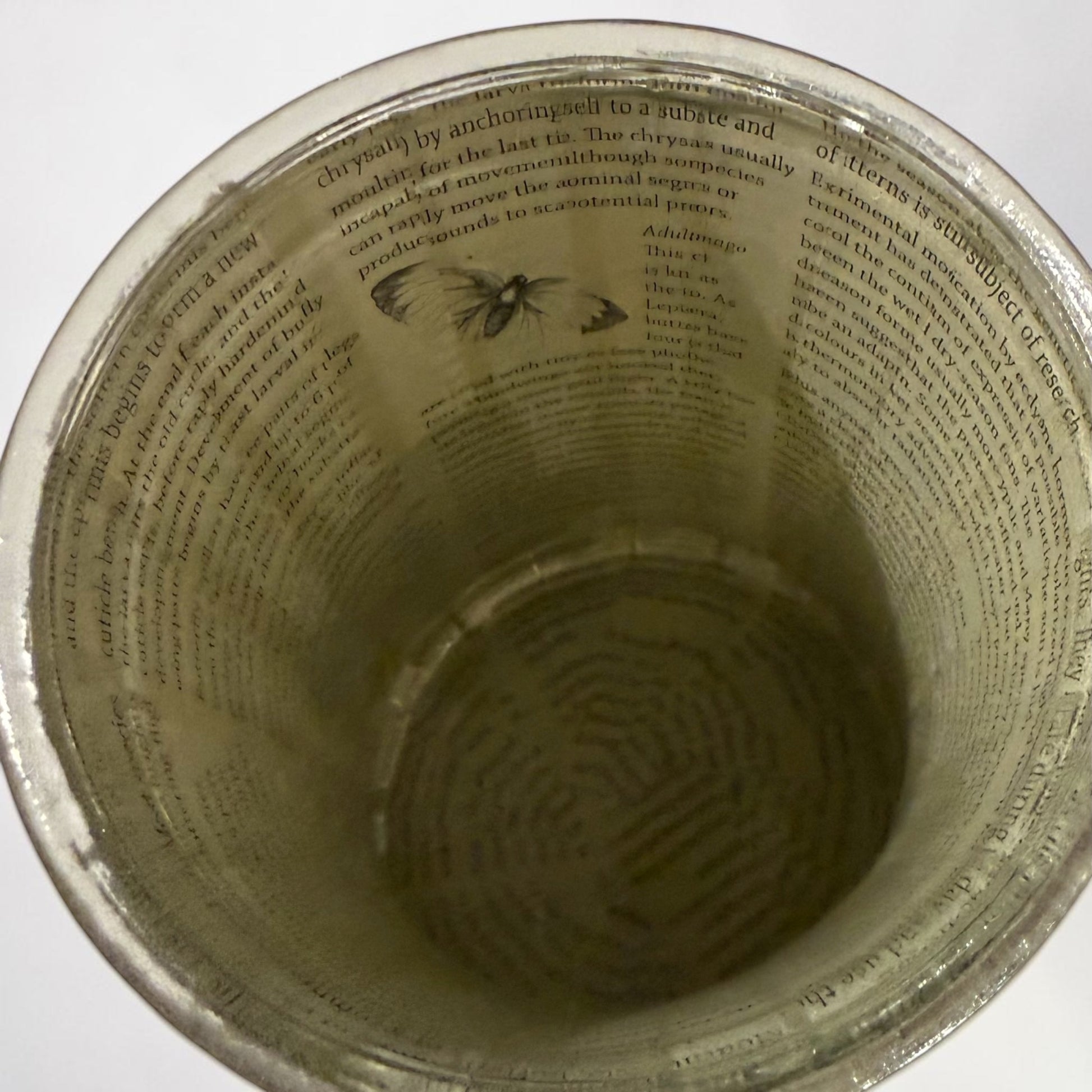 Inside of a glass vase decorated with book paper.  