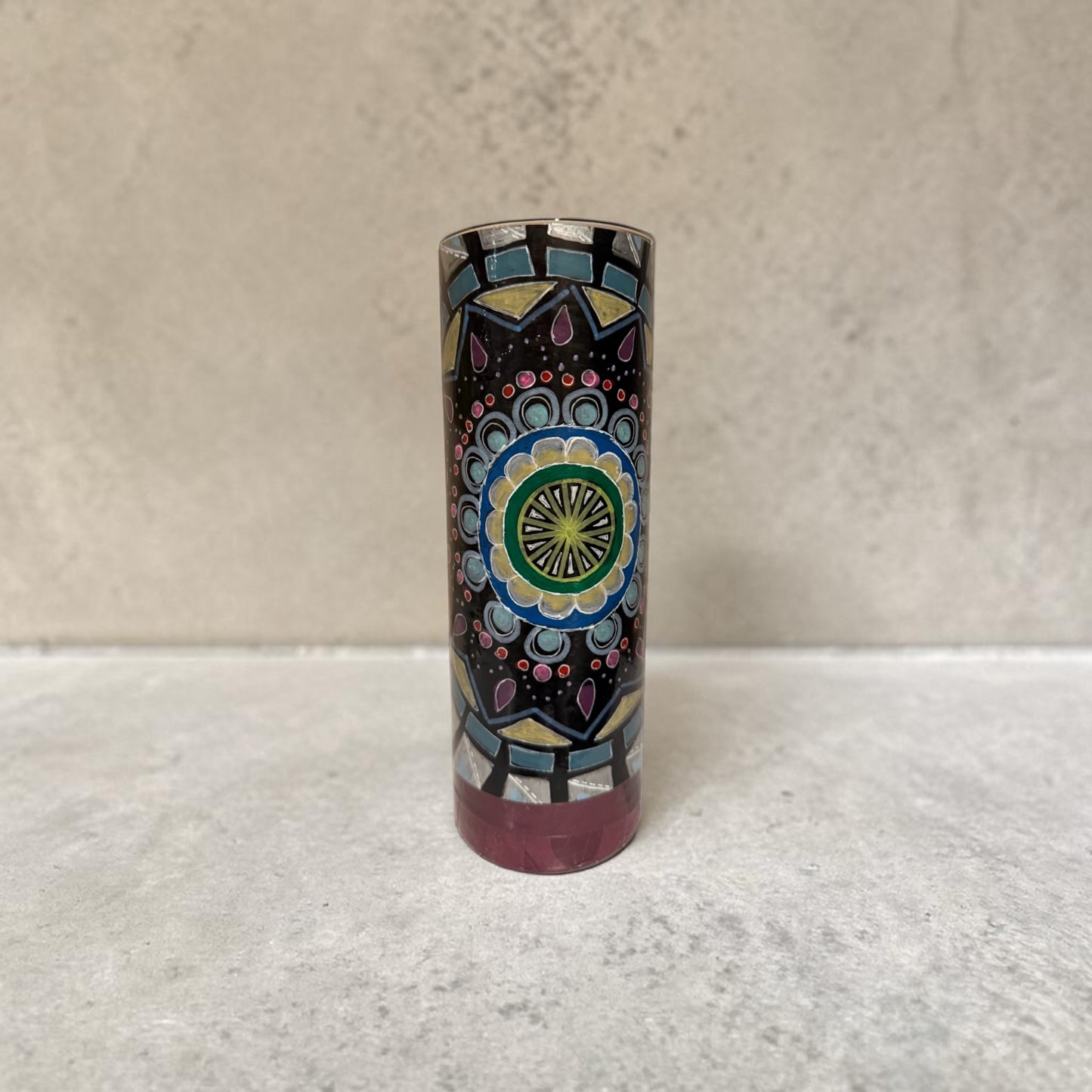 Cylindrical vase decorated with a colorful mandala on a white counter.
