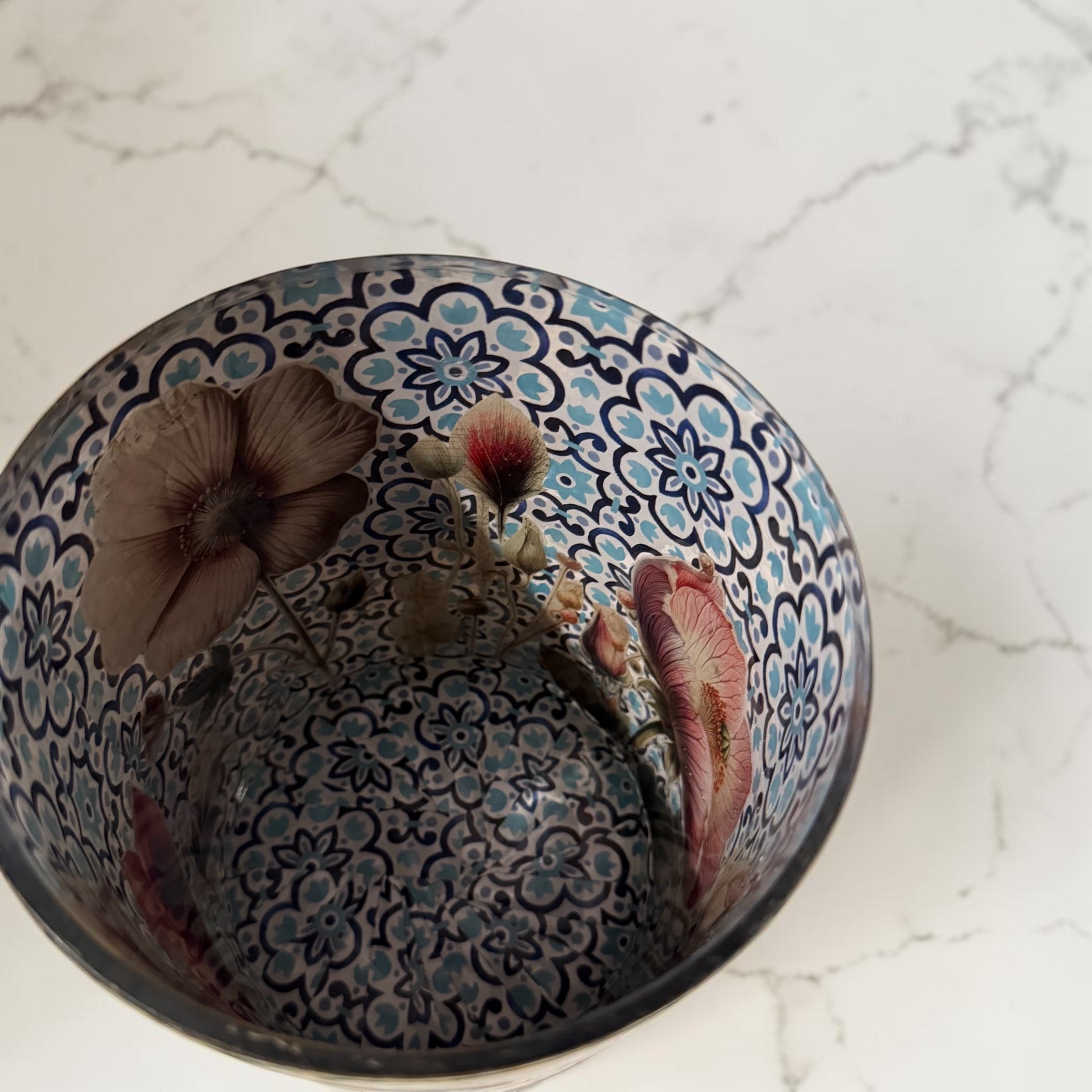 Inside of cookie jar decorated with blue tile paper and poppies on a white  marbled counter.