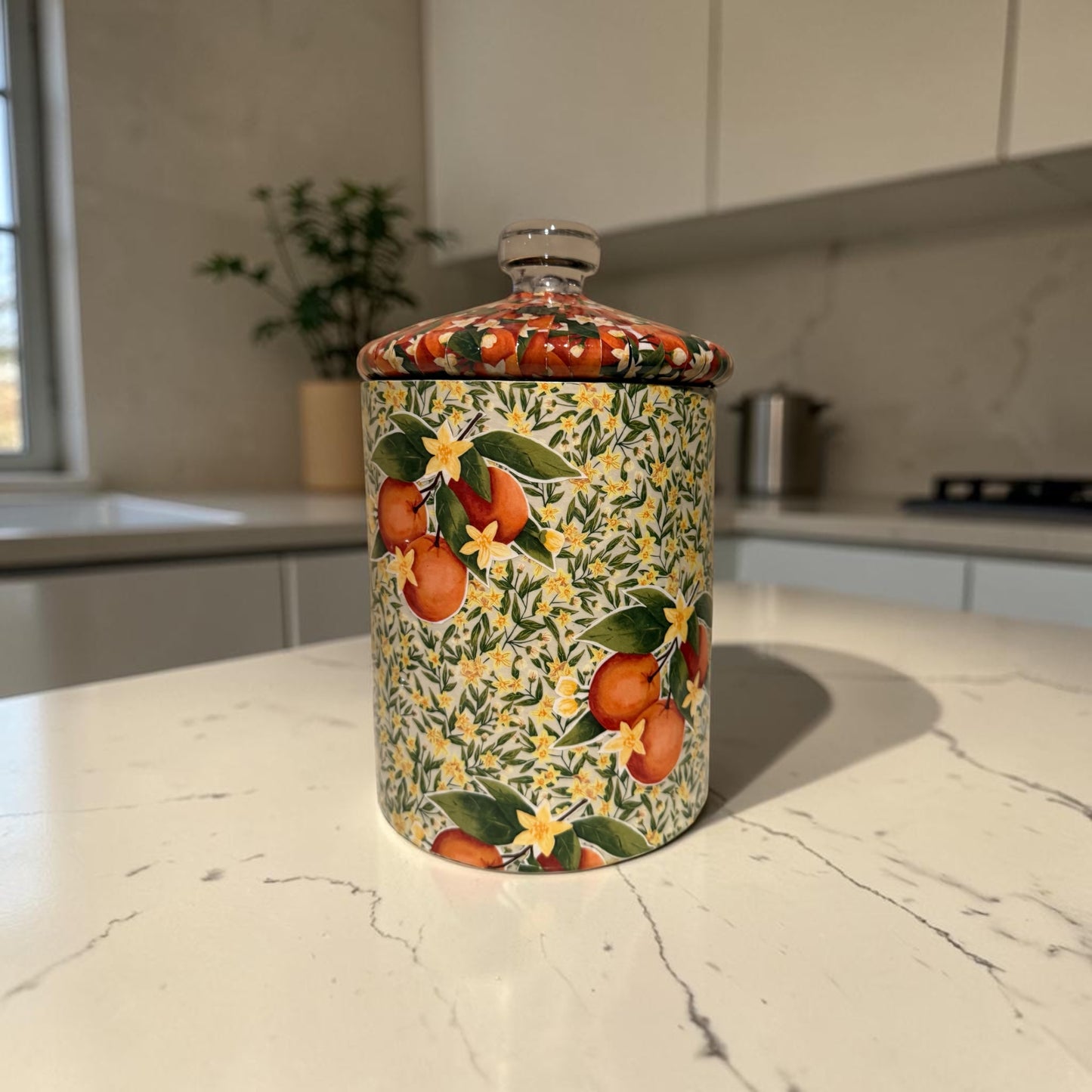 Cookie jar decorated with oranges on a kitchen counter.