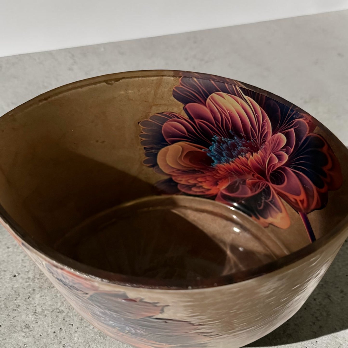 Inside of a glass oval vase decorated with a beige paper background and a large brilliant flower. 