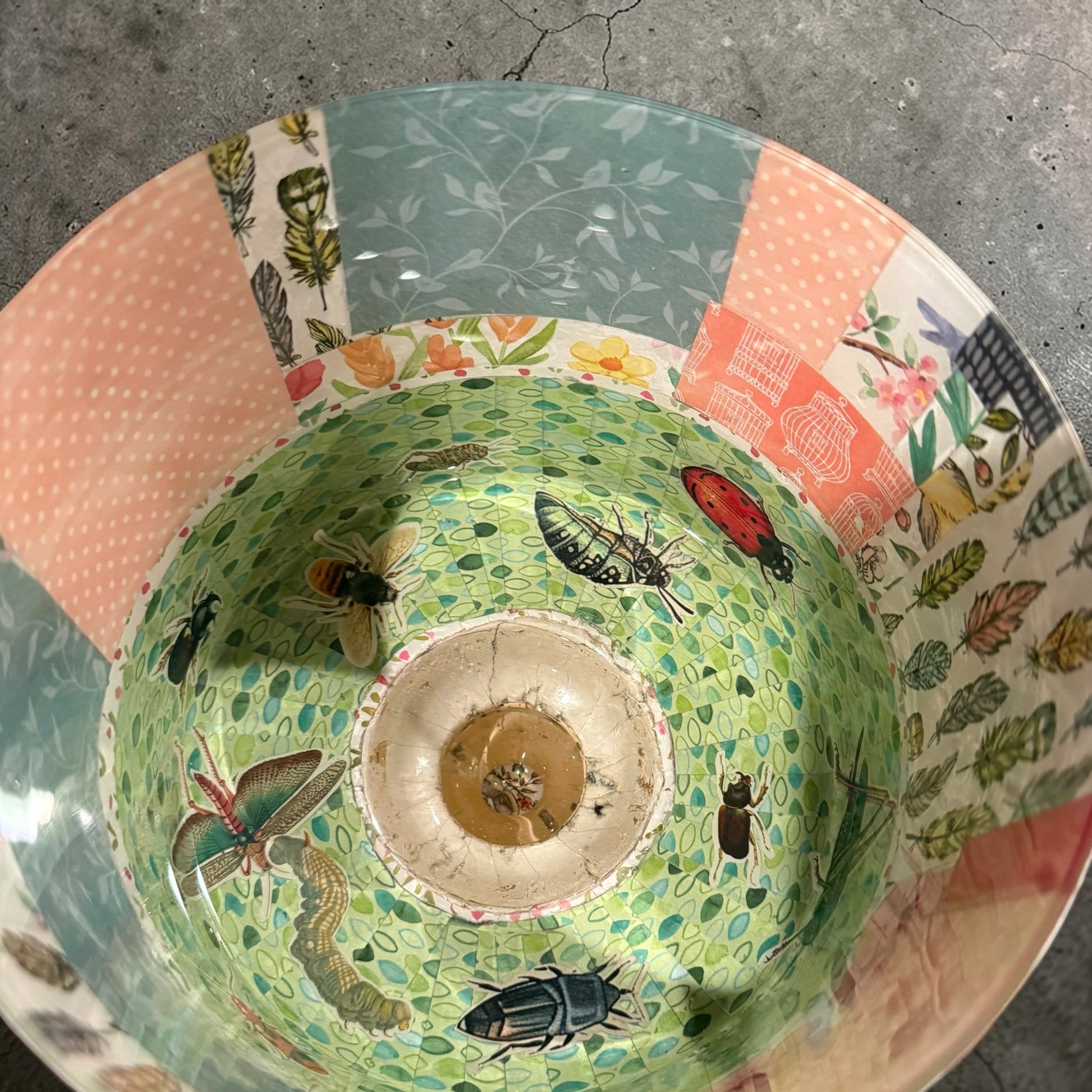 Decorative trifle bowl with colorful patterns and illustrations of insects on a concrete surface.