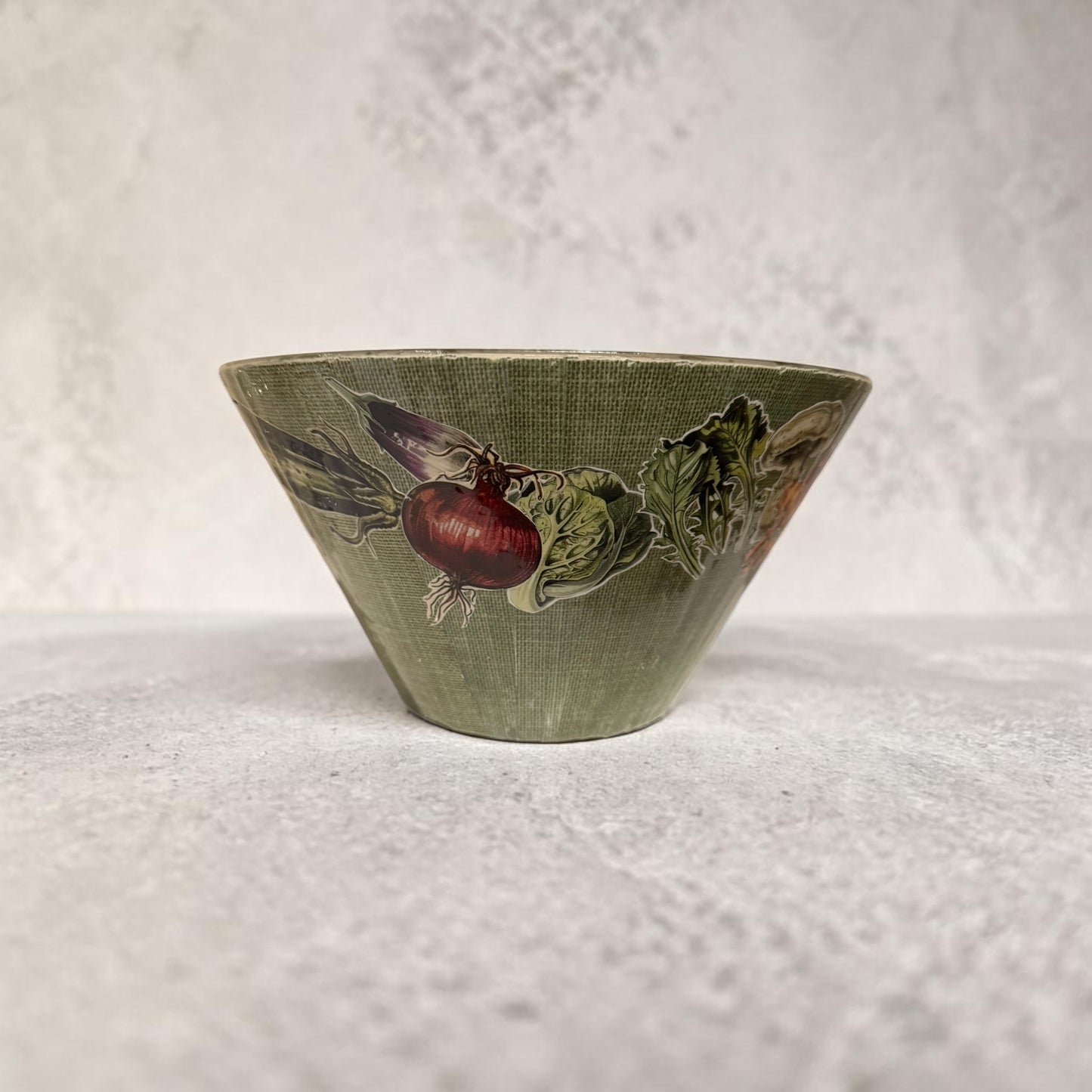 Green bowl with vegetable design on a concrete surface