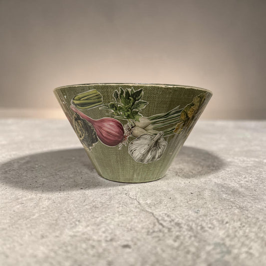 Green bowl with vegetable design on a concrete surface
