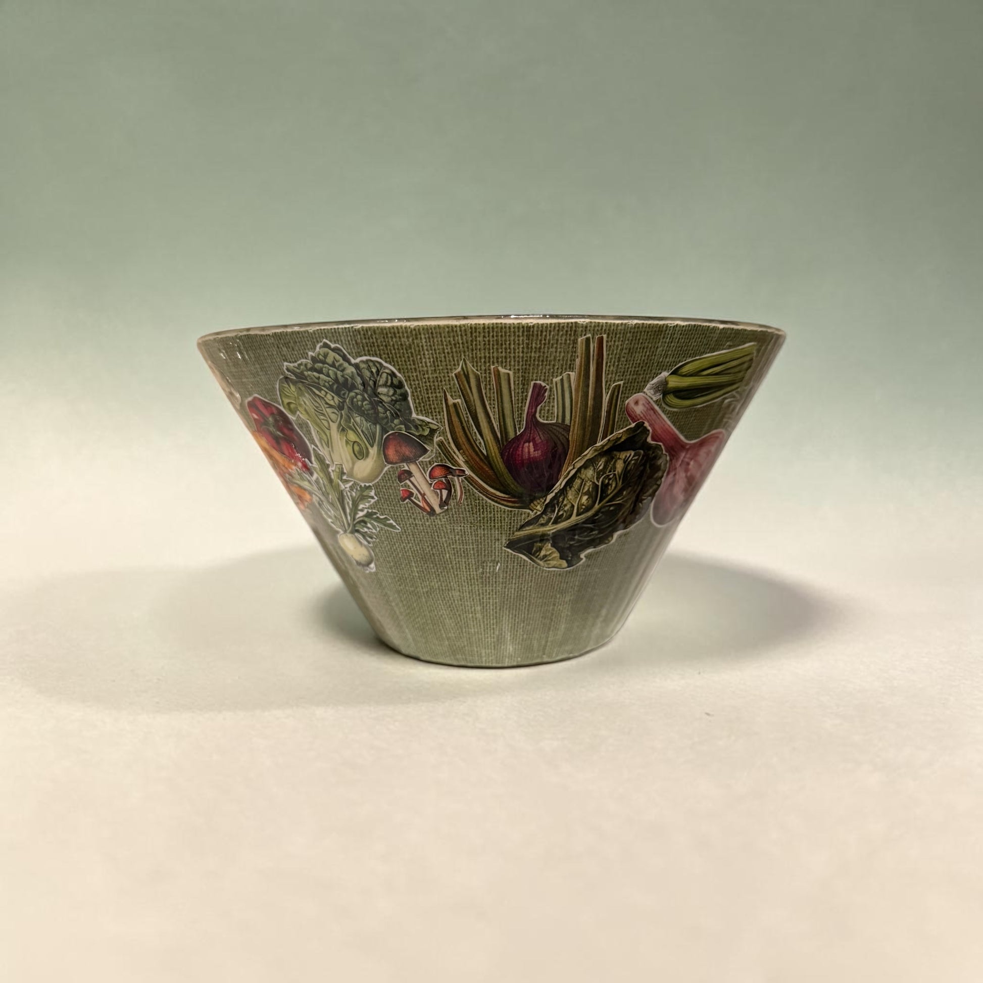 Decorative green bowl with vegetable design on a light background